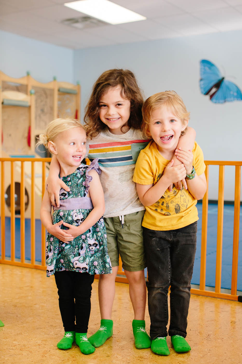 Three young kids grouped smiling in front of Kids Garden's preschool in Steamboat Springs, CO.