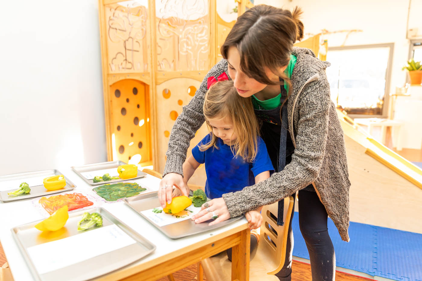 A teacher at Kids Garden's classes for kids, doing an art project with fruit and veggies.