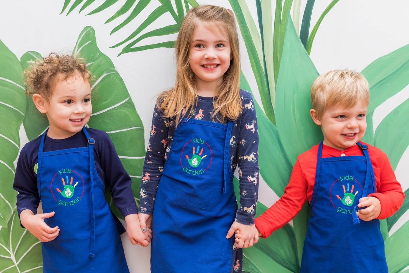 Kids standing in front of a leaf mural at Kids Garden's toddler classes in Charleston, SC.