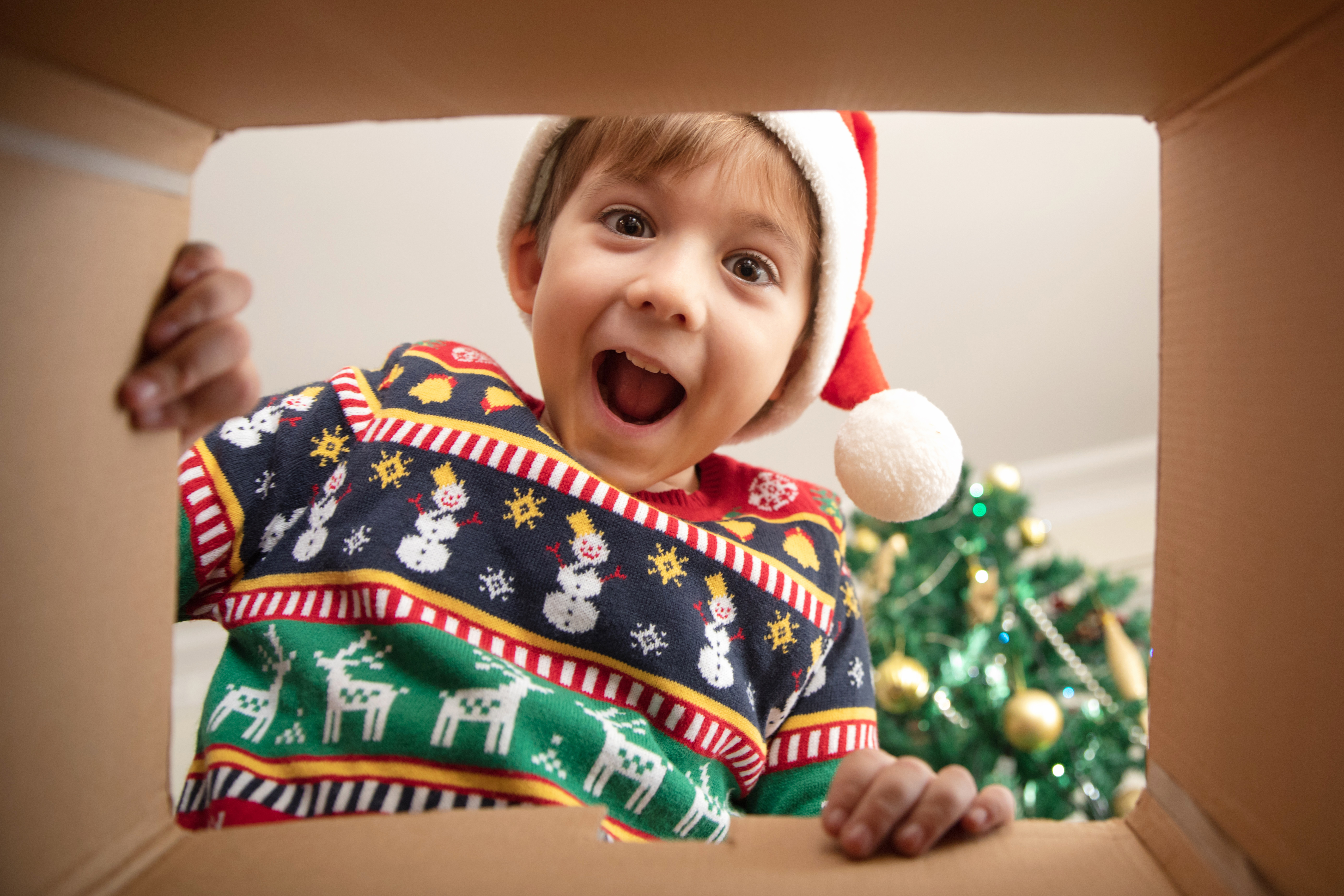 A child opening a holiday gift bought from Kids Garden Evergreen.