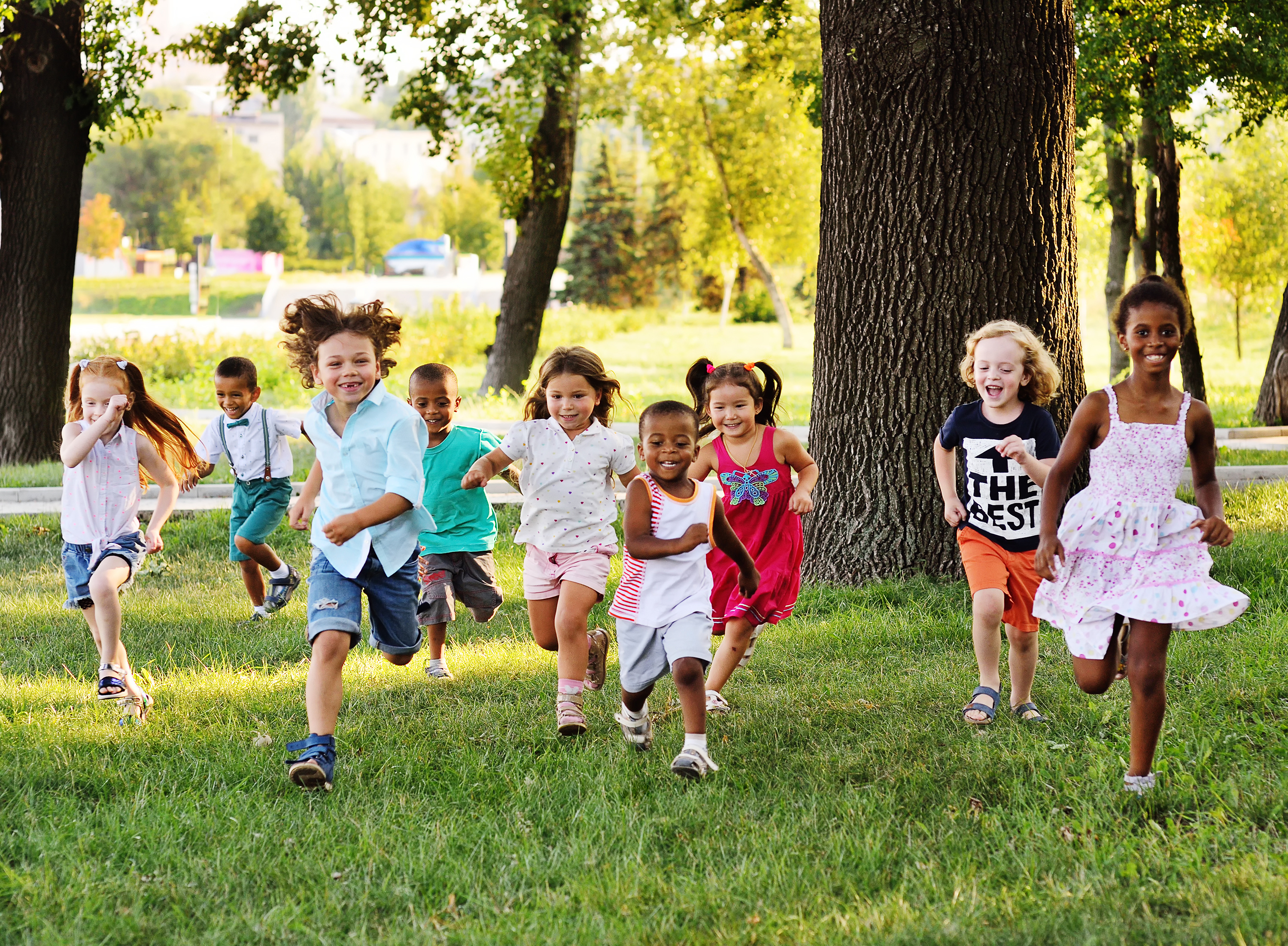 A group of kids running and having fun at a Kids Garden summer camp.